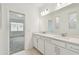 Bright bathroom featuring a double sink vanity with white cabinets, light countertops, and a large mirror at 3584 Maple Bay Ln, Land O Lakes, FL 34638