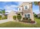 Two-story house with beige exterior, three-car garage, and well-maintained landscaping at 11339 Tayport Loop, New Port Richey, FL 34654