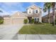 Two-story house with beige exterior, three-car garage, and manicured lawn at 11339 Tayport Loop, New Port Richey, FL 34654