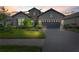 Beautiful home exterior featuring stone accents, lush lawn, and brick driveway leading to a garage at sunset at 26810 Weiskopf Dr, Englewood, FL 34223
