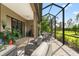 Covered lanai showcasing outdoor furniture and green space at 26810 Weiskopf Dr, Englewood, FL 34223