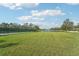 Serene pond view with lush green lawn and tennis court background at 6419 43Rd E Ct, Sarasota, FL 34243