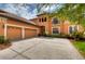Two-story house with terracotta tile roof, landscaped yard, and a three-car garage at 20103 Shady Hill Ln, Tampa, FL 33647