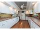 Long kitchen with white cabinets, wood floors, and a breakfast bar at 3006 Bolt Dr, Palm Harbor, FL 34685