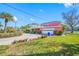 Pink house with a white garage door and a circular driveway, landscaping, and waterfront views at 5410 Pali Way, St Pete Beach, FL 33706