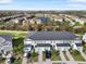 Aerial view of townhomes with well-maintained lawns, garages, and community lake in the distance at 8607 Canyon Creek Trl, Parrish, FL 34219