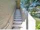 White metal stairs with handrail leading to condo unit, surrounded by stucco and landscaping at 2937 Bough Ave # D, Clearwater, FL 33760