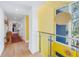 Bright hallway with wood floors, glass railing, and yellow accent wall at 838 Monterey Ne Blvd, St Petersburg, FL 33704