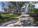 Two-story home with a long driveway, landscaping and mature trees, showing a side view at 838 Monterey Ne Blvd, St Petersburg, FL 33704