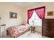Guest bedroom with a twin bed, dresser, and red curtains at 24617 Laurel Ridge Dr, Lutz, FL 33559