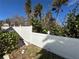 White backyard fence damaged, with tropical foliage on a sunny day showing damage repair needed at 239 Punta Vista Dr, St Pete Beach, FL 33706