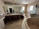 Bathroom featuring a corner soaking tub, tiled walls, and a dual sink vanity at 239 Punta Vista Dr, St Pete Beach, FL 33706