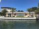 Waterfront home featuring an outdoor seating area, dock access, and lush palm trees in a desirable waterfront location at 239 Punta Vista Dr, St Pete Beach, FL 33706