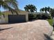 Charming home showcasing a brick driveway, mature palm trees, and a convenient two-car garage at 239 Punta Vista Dr, St Pete Beach, FL 33706