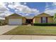 Tan house with white garage door and lush landscaping at 5220 Butterfly Shell Dr, Apollo Beach, FL 33572
