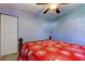 Bedroom with ceiling fan, wood bed frame, and red floral bedding at 5220 Butterfly Shell Dr, Apollo Beach, FL 33572