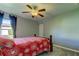 Bedroom with ceiling fan, wood bed frame, and red floral bedding at 5220 Butterfly Shell Dr, Apollo Beach, FL 33572