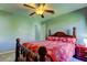 Bedroom with ceiling fan, wood bed frame, and red floral bedding at 5220 Butterfly Shell Dr, Apollo Beach, FL 33572