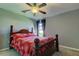 Bedroom with ceiling fan, wood bed frame, and red floral bedding at 5220 Butterfly Shell Dr, Apollo Beach, FL 33572