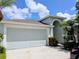 Two-car garage with a large driveway, a well-manicured yard, and a light blue paint job at 27542 Sky Lake Circle, Wesley Chapel, FL 33544