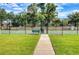 Community tennis court surrounded by a fence, accessible via a paved walkway through a gate at 27542 Sky Lake Circle, Wesley Chapel, FL 33544