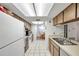 Long kitchen with wood cabinets, white appliances, and tiled floors at 3840 Staysail Ln # 3840, Holiday, FL 34691