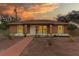 Charming single-story home featuring brick-paved driveway and a welcoming front entrance beneath a stunning sunset at 460 48Th S St, St Petersburg, FL 33711