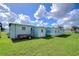 Rear view of the mobile home with a trailer and shed at 5330 Vera St, Zephyrhills, FL 33542