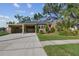 Tan house with carport, landscaping, and a red door at 3715 W Santiago St, Tampa, FL 33629