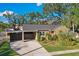 Tan house with carport, landscaping, and a red door at 3715 W Santiago St, Tampa, FL 33629