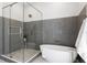 Bathroom featuring a modern glass-enclosed shower and freestanding tub with stylish gray and white tiling at 4633 W Lowell Ave, Tampa, FL 33629