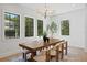 Bright dining room with large wood table, modern light fixture, and multiple black-trimmed windows offering verdant view at 4633 W Lowell Ave, Tampa, FL 33629