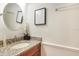 Half-bath with a granite countertop vanity and decorative mirror at 15272 Spinning Wheel Ln, Brooksville, FL 34604