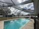 Large screened-in pool with a basketball hoop at 15272 Spinning Wheel Ln, Brooksville, FL 34604