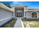 Inviting gray home with a covered entry, arched entryway, and manicured landscaping leading to the front door at 15272 Spinning Wheel Ln, Brooksville, FL 34604