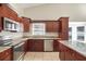 Kitchen featuring stainless steel appliances, dark wood cabinets, and a granite countertop, providing ample counter space at 15272 Spinning Wheel Ln, Brooksville, FL 34604