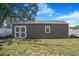 View of shed shows gray siding, a window, and a set of double doors at 15272 Spinning Wheel Ln, Brooksville, FL 34604