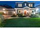 Charming two-story home featuring a lush green lawn, manicured landscaping, and inviting front porch at twilight at 3106 W Bay Villa Ave, Tampa, FL 33611