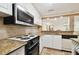 Modern kitchen with stainless steel microwave, tile backsplash, and granite countertops at 36750 Us Highway 19 N # 03127, Palm Harbor, FL 34684