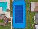 Aerial view of a vibrant blue tennis court next to a swimming pool at 914 Willowood Ln, Dunedin, FL 34698