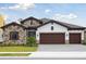 Charming single-story home featuring a stone facade, three-car garage, and well-manicured lawn at 13110 Homestead Ln, Parrish, FL 34219