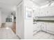 Bright kitchen with white cabinets, white appliances, and an adjacent living room with a ceiling fan at 11485 Oakhurst Rd # 322, Largo, FL 33774