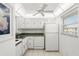 Kitchen with white cabinets, appliances, and a ceiling fan at 11485 Oakhurst Rd # 322, Largo, FL 33774