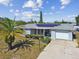 House with solar panels, driveway, and palm trees in the front yard at 7511 Tyson Dr, Port Richey, FL 34668