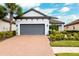 Two-story house with gray garage door and brick driveway, landscaping, and palm trees at 8520 Grand Alberato Rd, Tampa, FL 33647