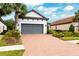 Two-story house with gray garage door and brick driveway, landscaping, and palm trees at 8520 Grand Alberato Rd, Tampa, FL 33647