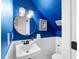 Small bathroom with blue walls, white wainscoting, and a round mirror at 3506 N Arlington Ave, Tampa, FL 33603