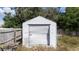 A white storage shed in a backyard area with overgrown vegetation and a wooden fence at 11217 Roman St, Spring Hill, FL 34609