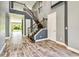 Grand foyer features wood-look tile floors, soaring ceilings, and a staircase with dark wood steps and black iron balusters at 6317 Brevada Ln, Apollo Beach, FL 33572