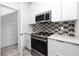 Modern kitchen with white cabinets, stainless steel appliances, and geometric backsplash at 3402 E 28 Ave # 1, Tampa, FL 33605